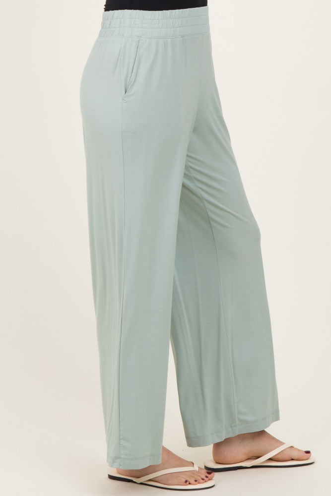 woman wearing light green wide-leg pants with an elastic waistband and side pockets, styled with flip flops