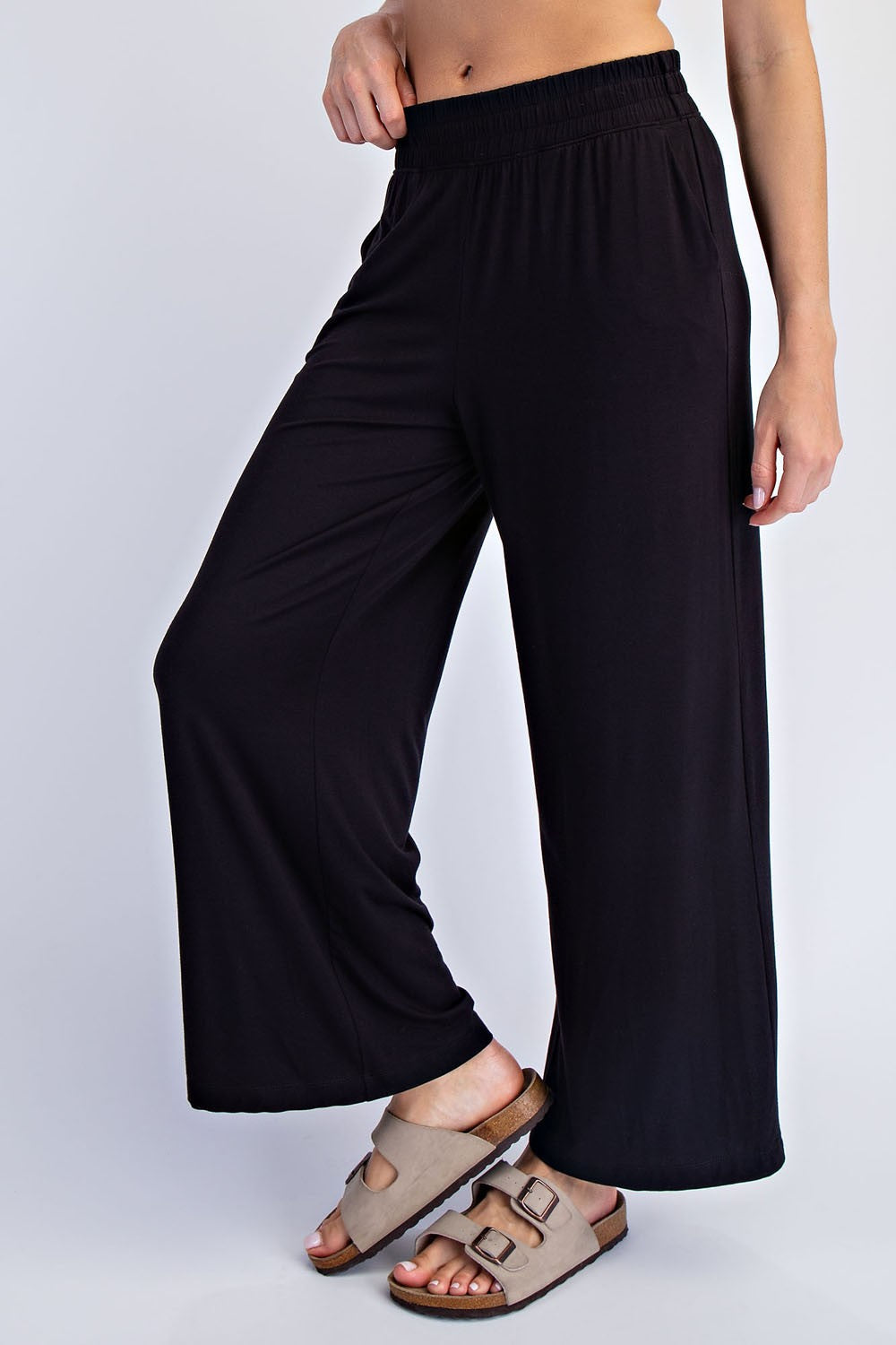 woman wearing black wide-leg lounge pants and beige slip-on sandals