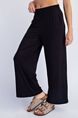 woman wearing black wide-leg lounge pants and beige slip-on sandals