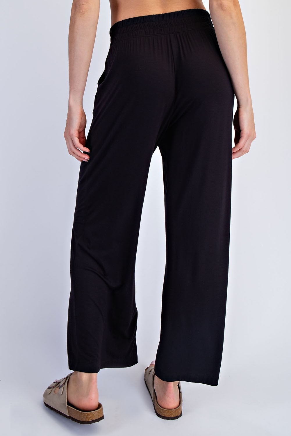 woman wearing black wide-leg pants, showing the back view and paired with beige sandals