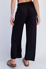 woman wearing black wide-leg pants, showing the back view and paired with beige sandals