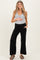woman wearing a gray maternity tank top and black wide-leg maternity pants, holding her baby bump