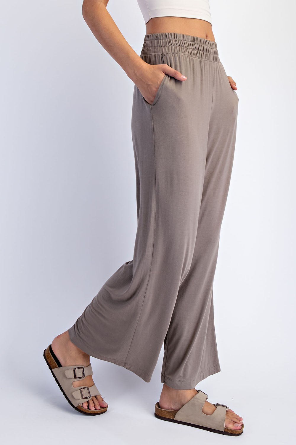 woman wearing taupe wide-leg lounge pants with pockets and a stretchy waistband, paired with slip-on sandals