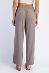 woman wearing light brown wide-leg pants with an elastic waistband, viewed from the back