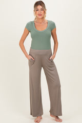 woman wearing a light green ribbed maternity top and taupe wide-leg maternity pants with pockets