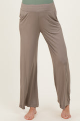 woman wearing light brown maternity wide-leg pants with pockets, model standing barefoot
