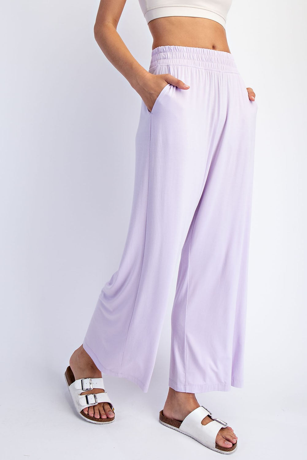woman wearing lavender wide leg pants with an elastic waistband and side pockets, styled with white slide sandals