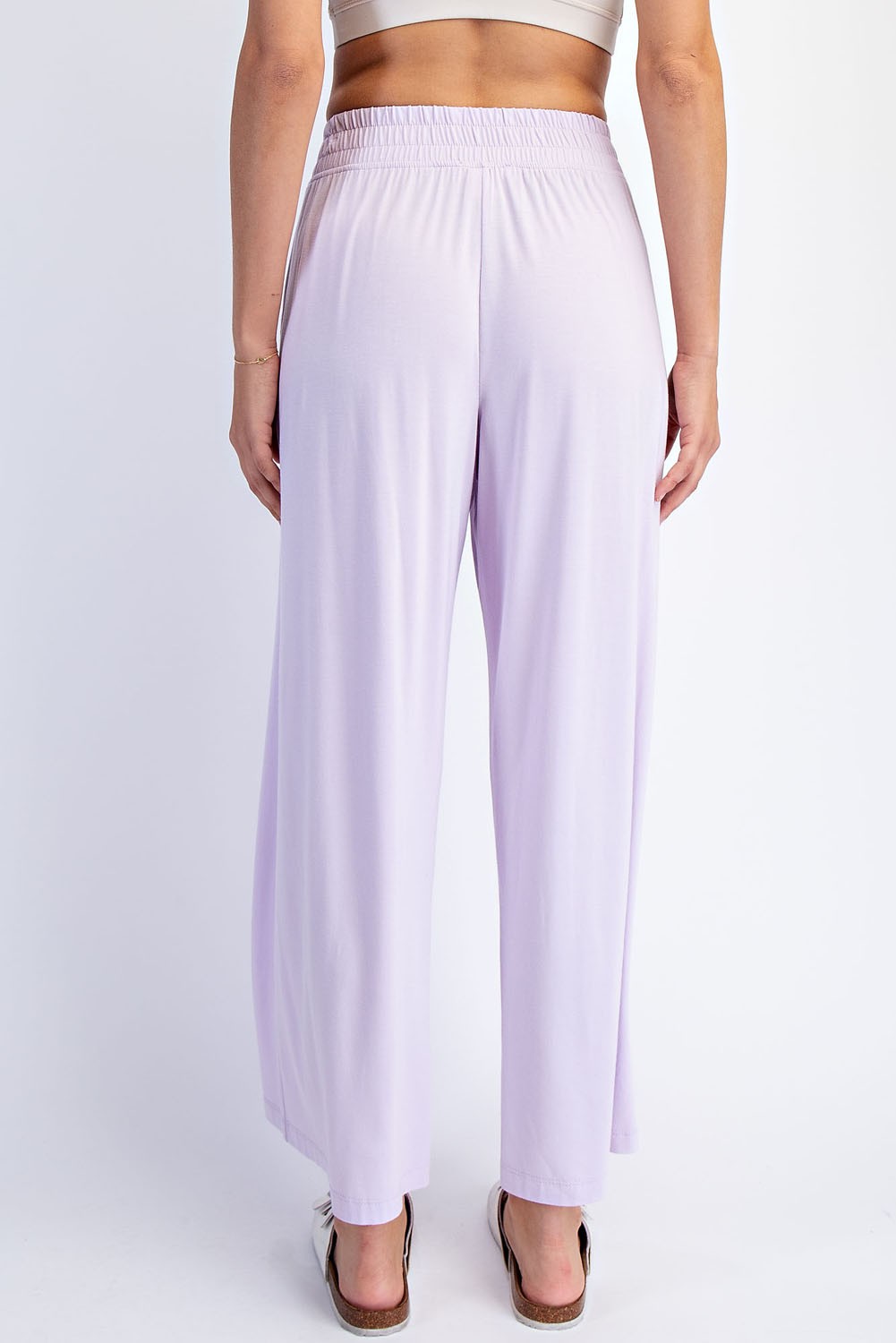 woman wearing light lavender wide-leg pants with an elastic waistband, viewed from the back