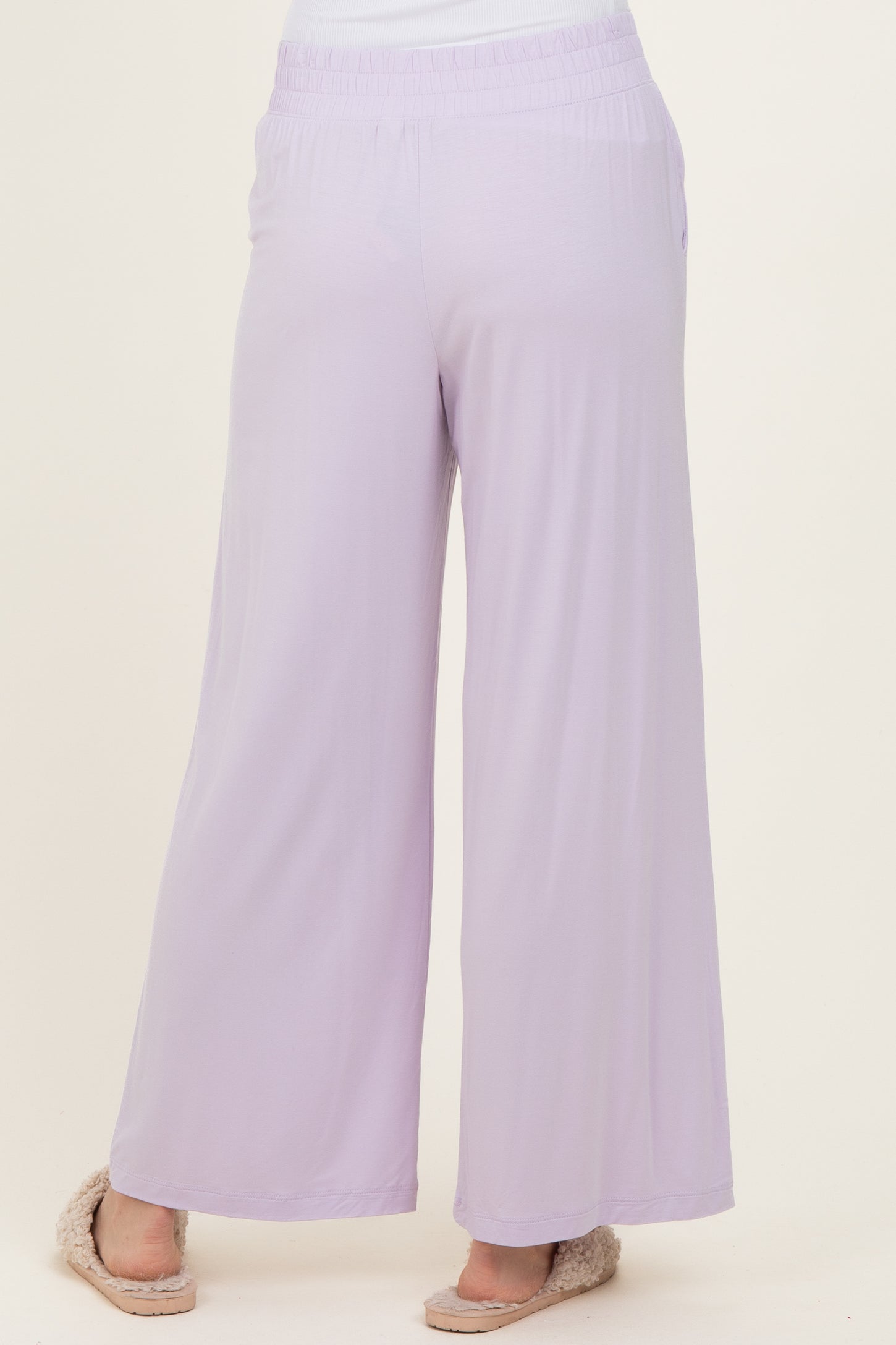 woman wearing lilac wide-leg pants with an elastic waistband and side pockets, standing with her back to the camera