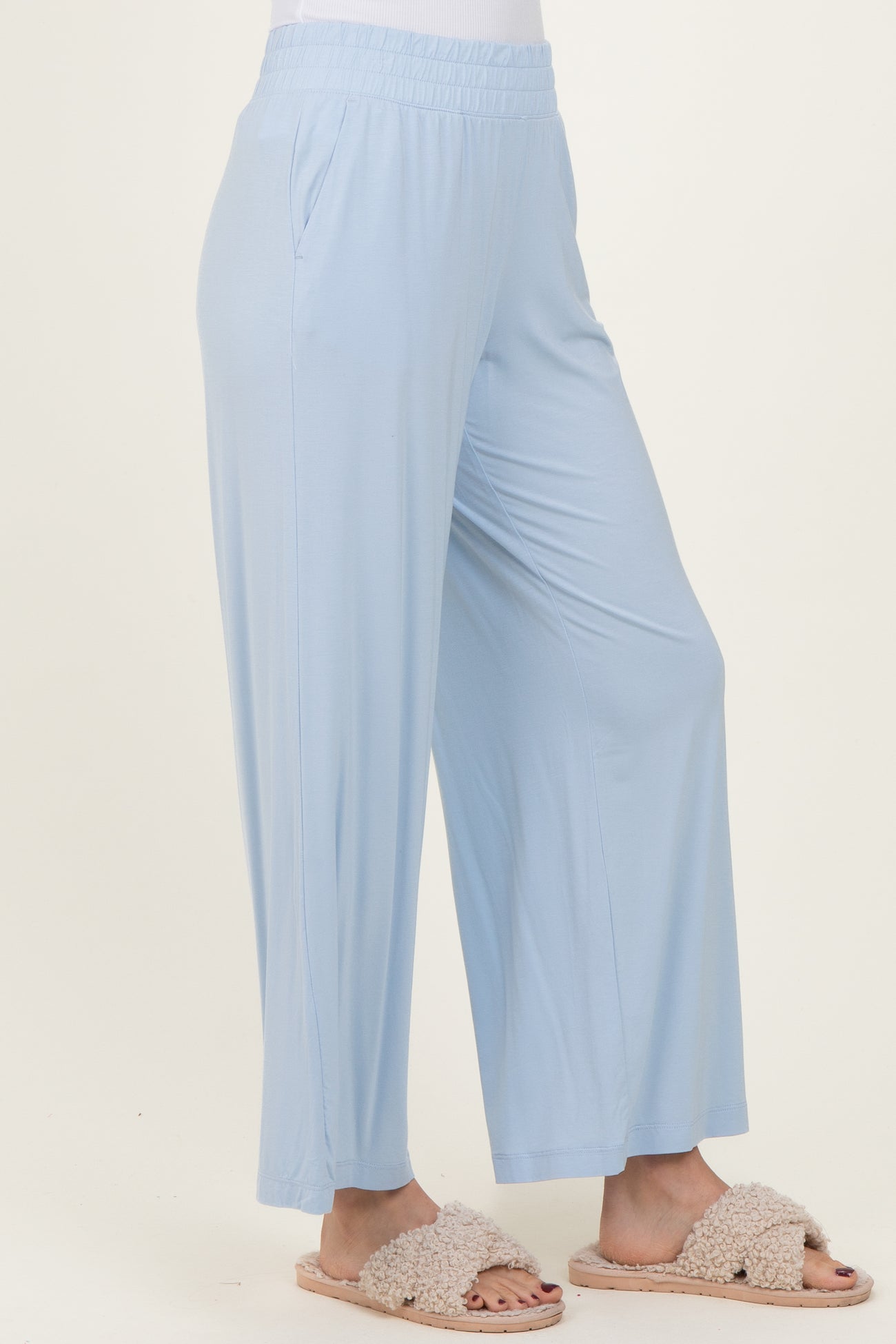 woman wearing light blue wide-leg pants with an elastic waistband and casual slippers
