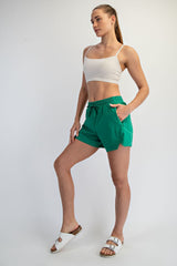 woman wearing a white crop top and green athletic shorts with pockets, styled with white slide sandals