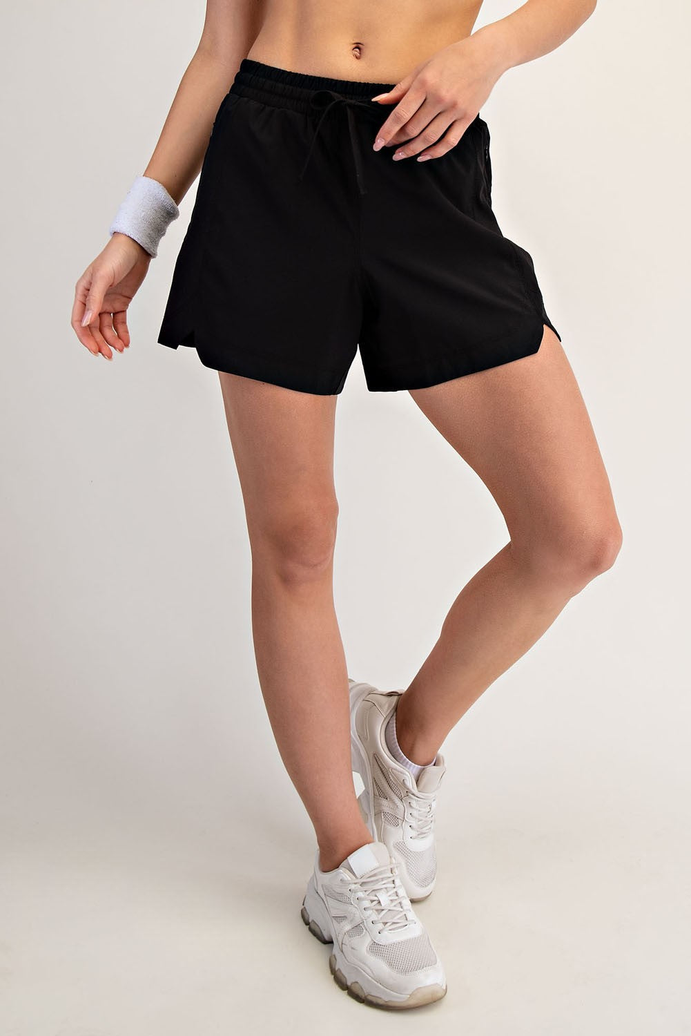 woman wearing black athletic shorts and white sneakers, standing with one leg forward