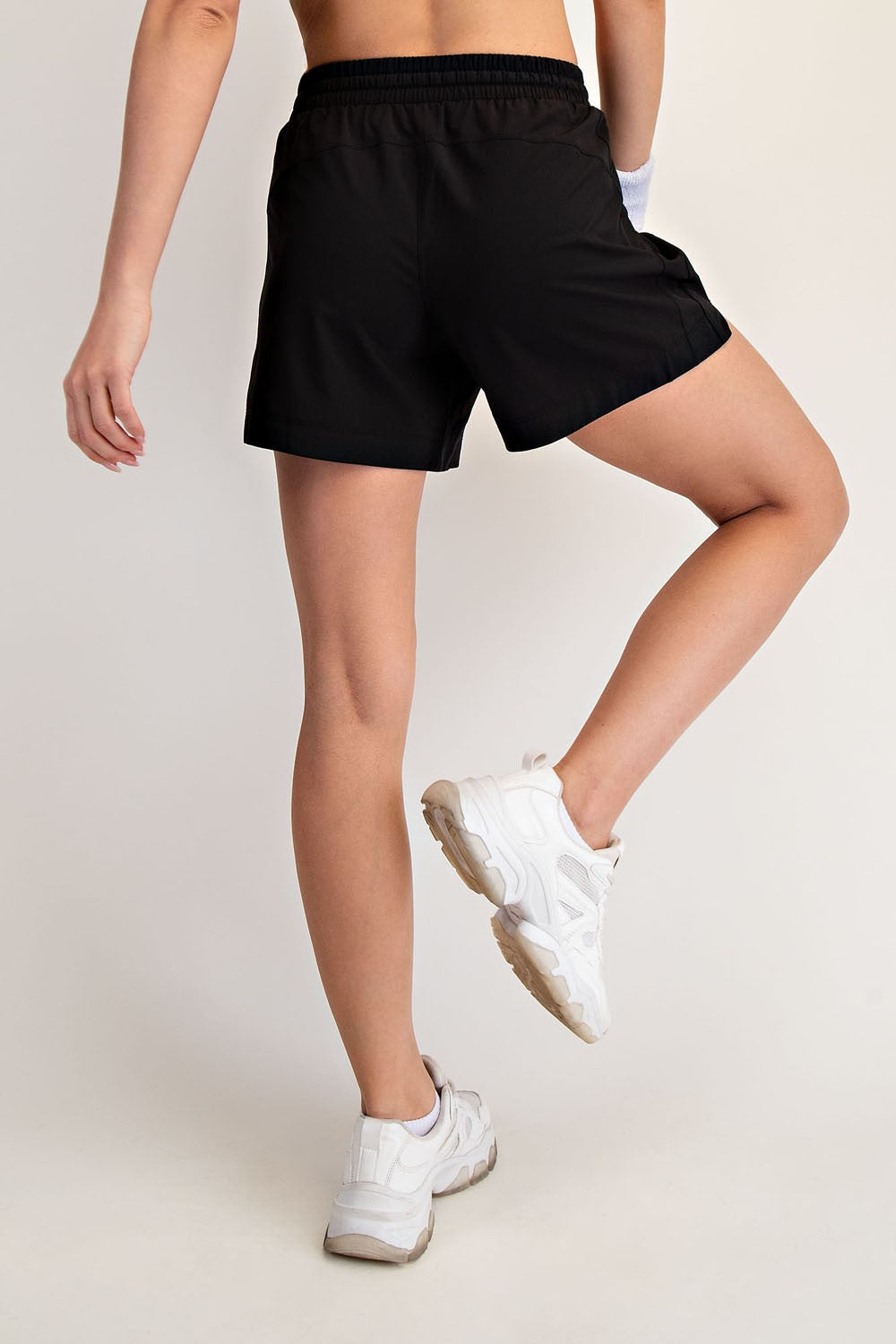 woman wearing black athletic shorts and white sneakers, posed from the back