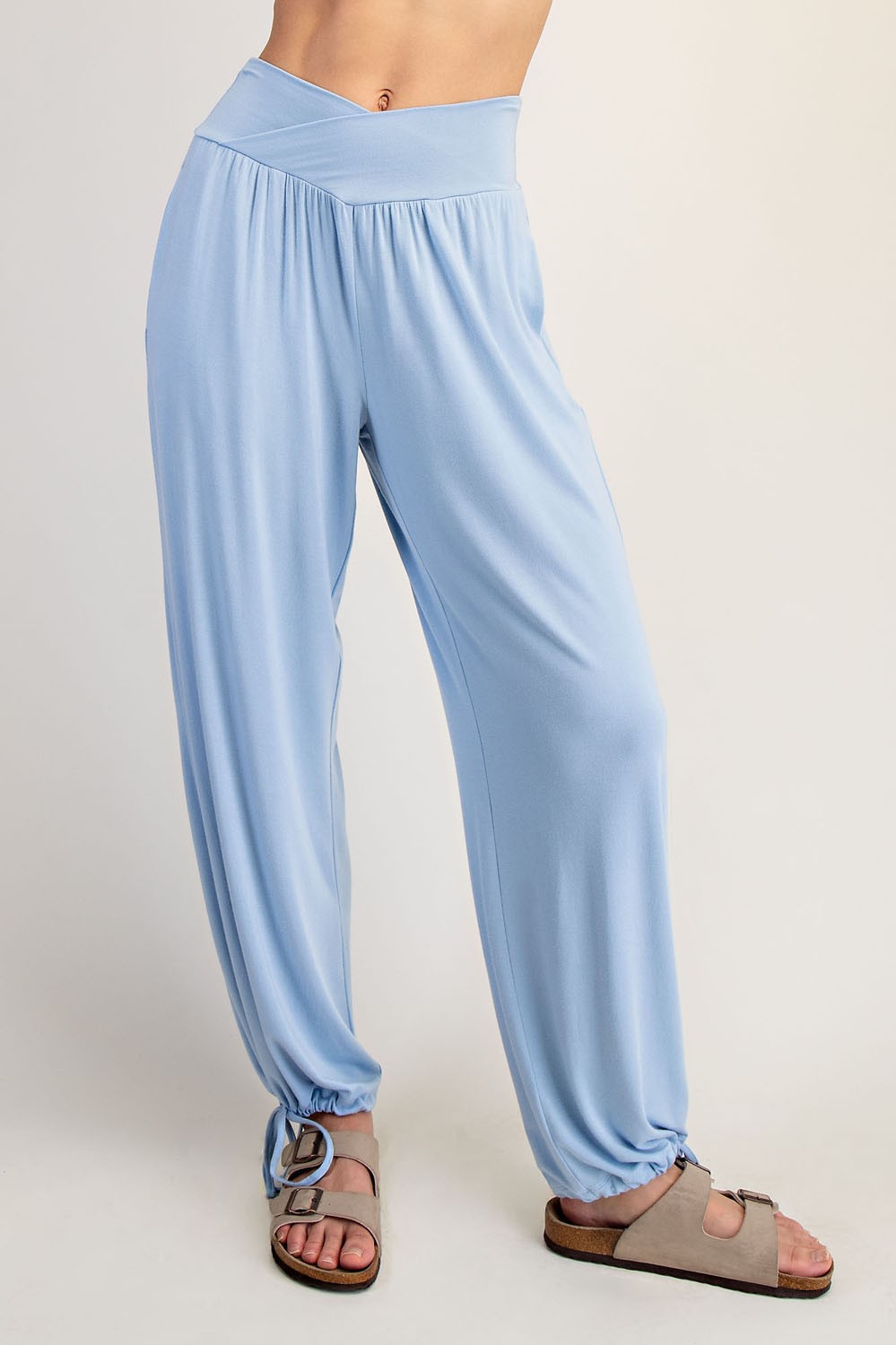 woman wearing light blue relaxed-fit pants with a wide waistband and gathered hems, paired with sandals