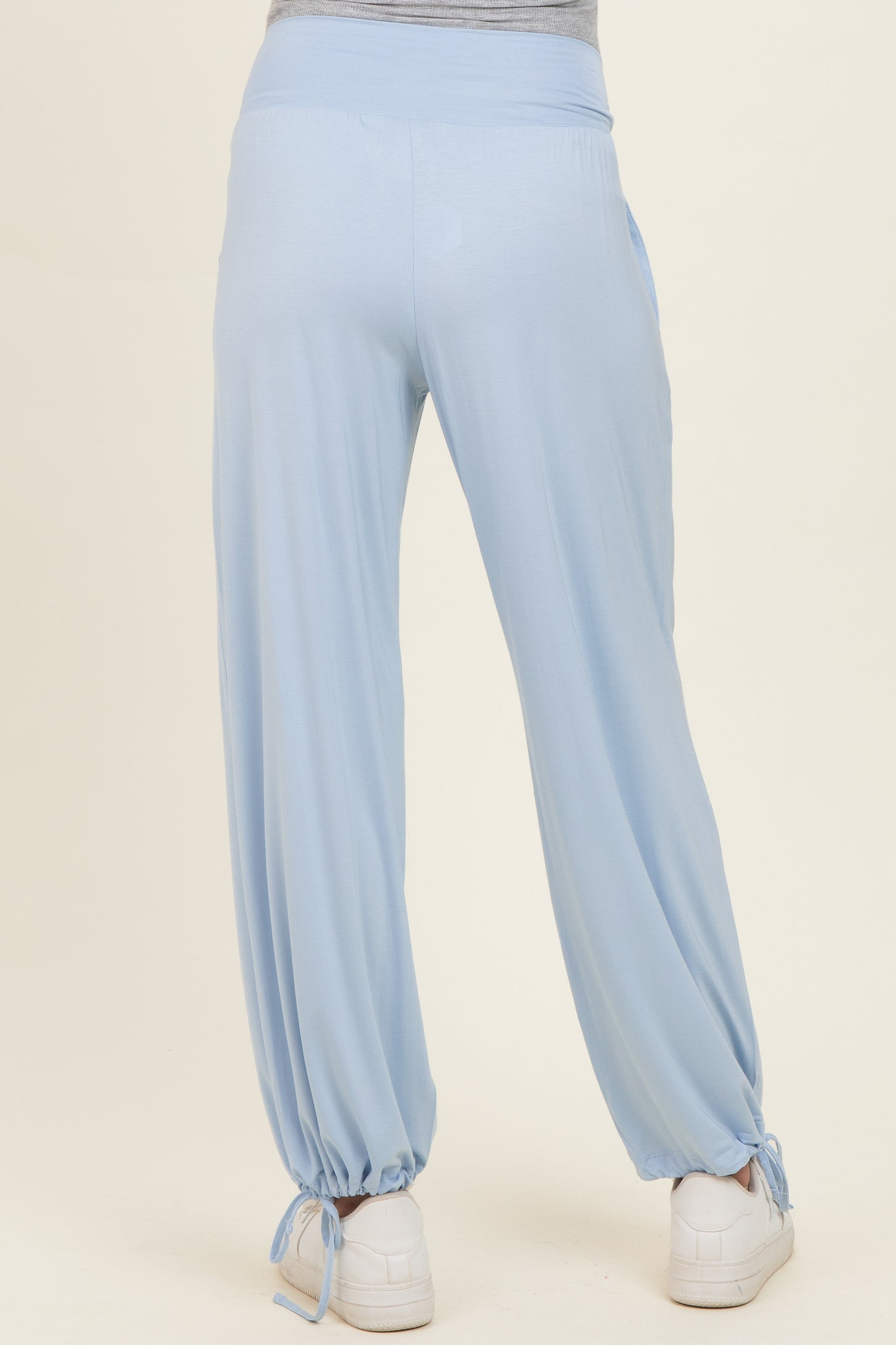 woman wearing light blue maternity pants with a relaxed fit and ties at the ankles, showing a baby bump