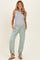 woman wearing a grey sleeveless top and mint green maternity jogger pants with side pockets