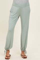 woman wearing light green maternity pants with a wide waistband and adjustable ties at the ankles