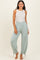 woman wearing a light gray sleeveless top and mint green high-waisted pants with adjustable cuffs.