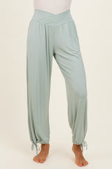 woman wearing light green wide-leg pants with a high waist and tie details at the ankles