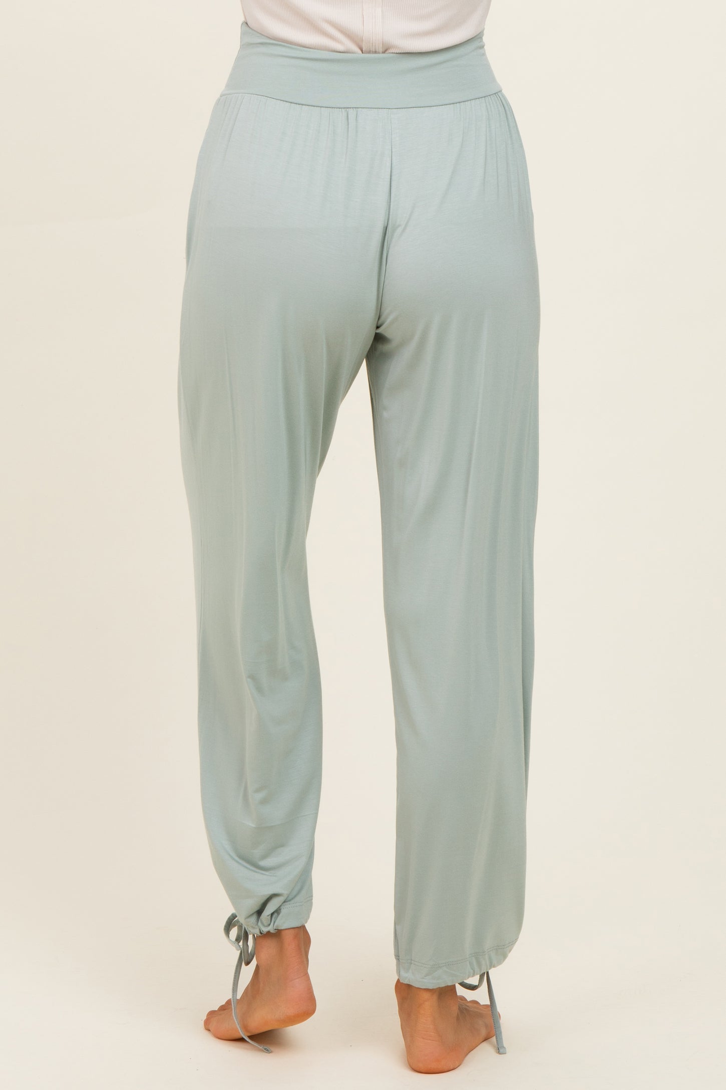 woman wearing light green flowy pants with a cinched hem and side tie details, viewed from the back