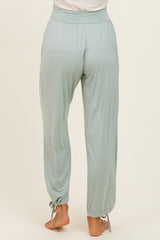 woman wearing light green flowy pants with a cinched hem and side tie details, viewed from the back