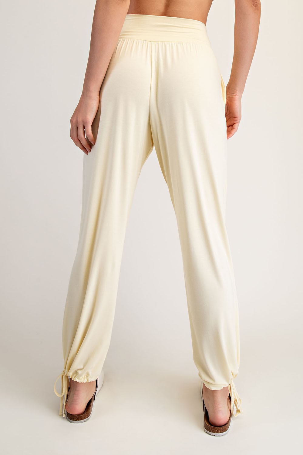 woman wearing light yellow drawstring lounge pants with tapered ankles and a relaxed fit, shown from the back