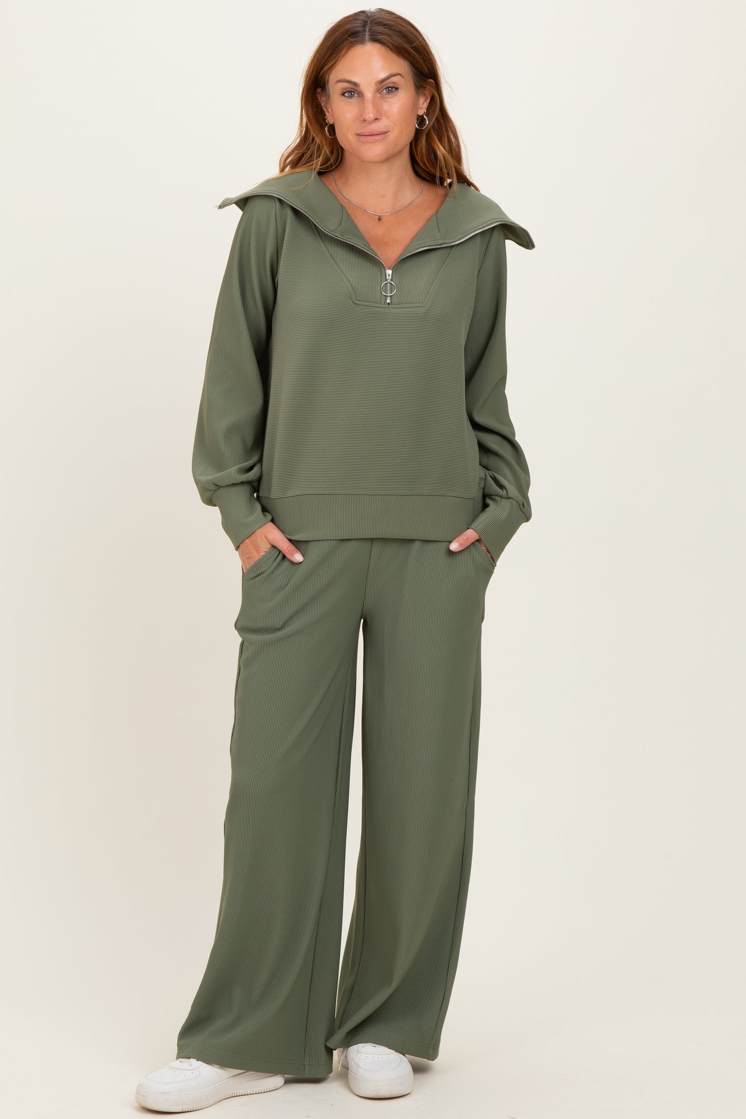 woman wearing a sage green zip-up hoodie and wide-leg pants set with long sleeves and pockets
