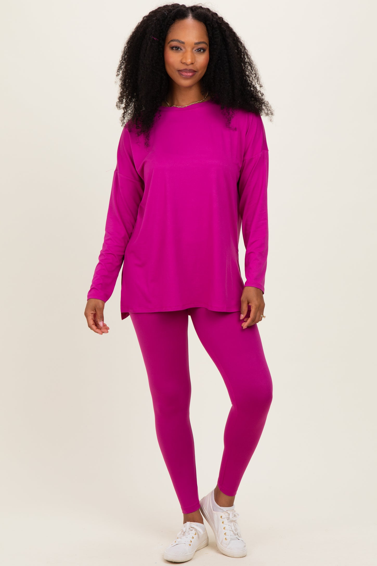 woman wearing a bright pink long sleeve top and matching leggings with white sneakers