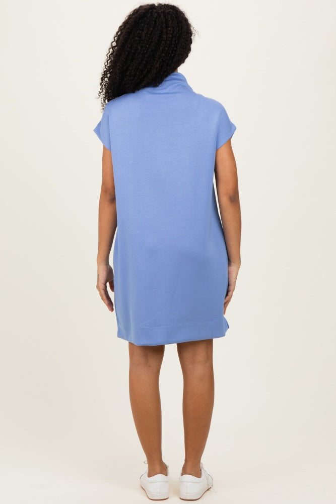 woman wearing a light blue short sleeve dress with a cowl neck and a relaxed fit, seen from the back