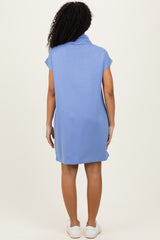 woman wearing a light blue short sleeve dress with a cowl neck and a relaxed fit, seen from the back