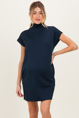 woman wearing a navy blue short sleeve maternity dress with a high neckline and relaxed fit, showing her baby bump