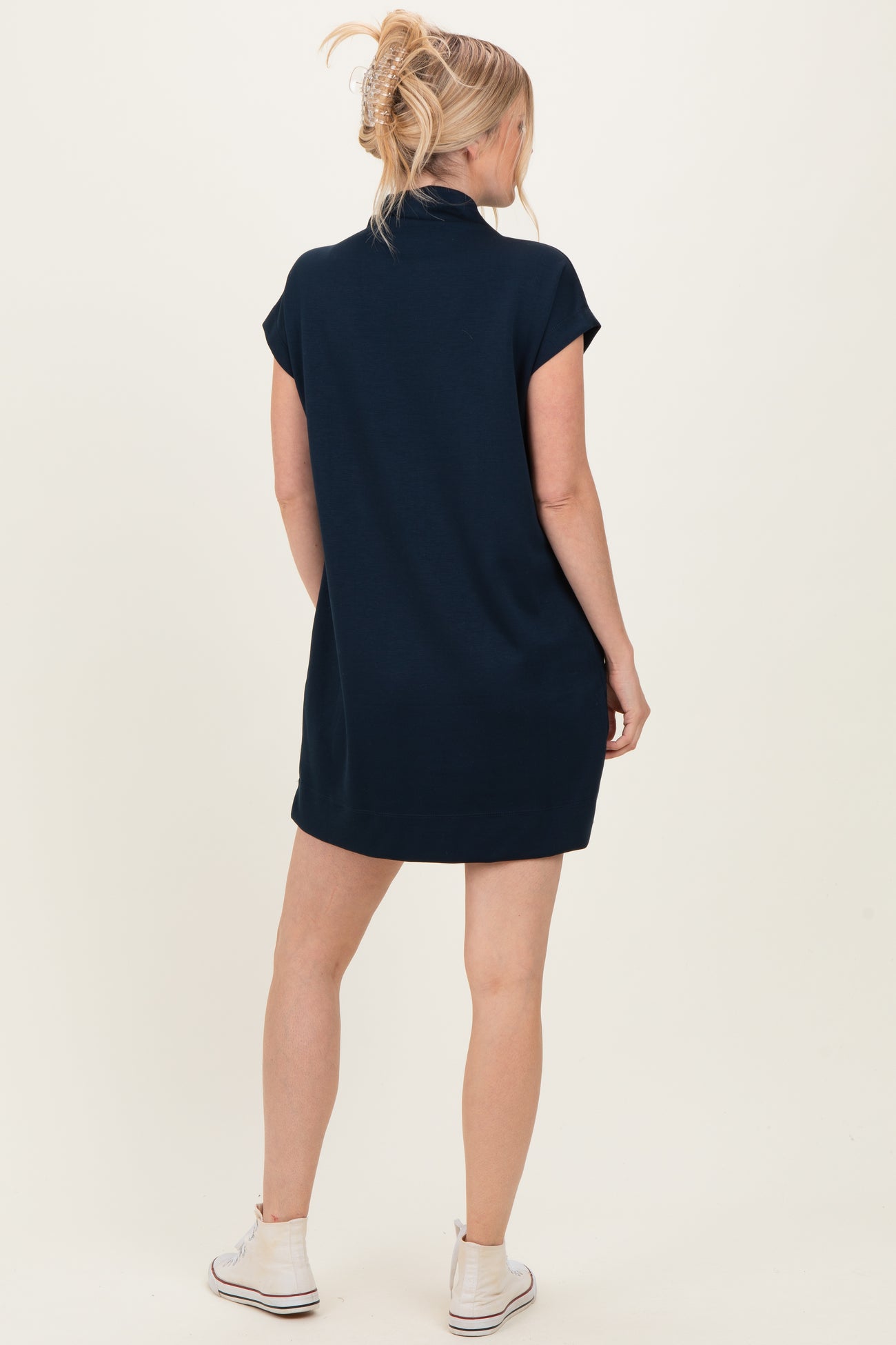 woman wearing a navy blue oversized polo dress with short sleeves, standing with her back to the camera