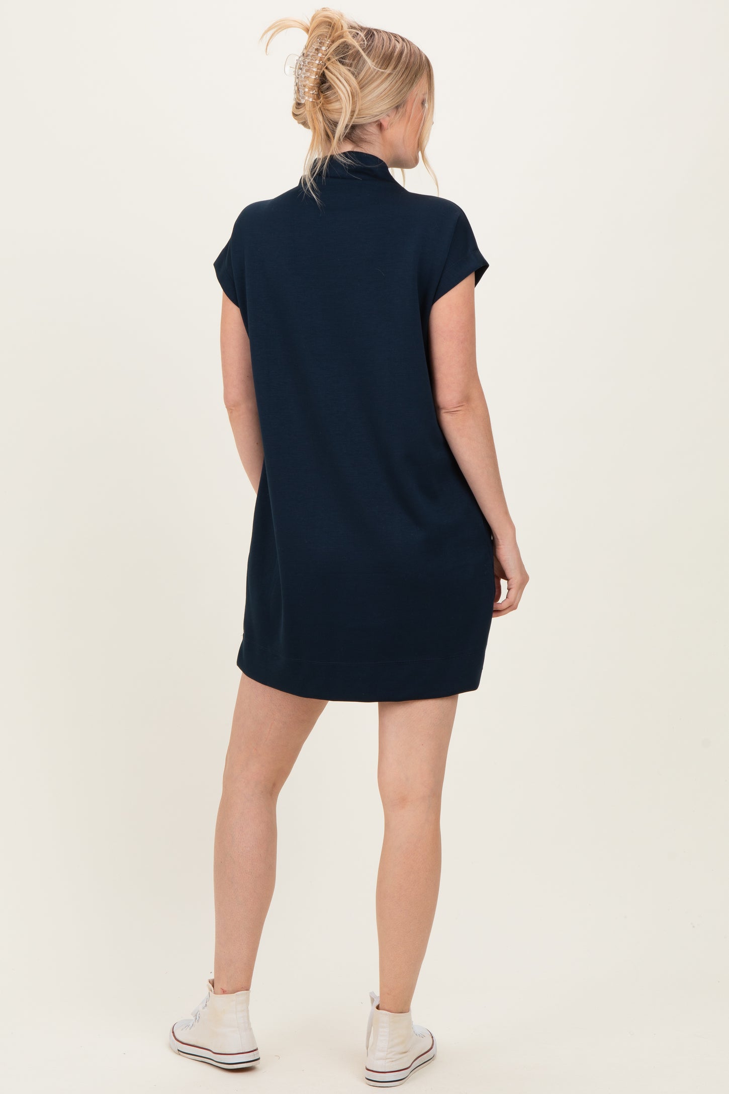 woman wearing a navy blue oversized polo dress with short sleeves, standing with her back to the camera