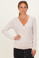woman wearing a light pink long sleeve wrap top with a deep v-neck and a fitted style