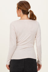 woman wearing a light beige long sleeve top with a fitted design and scoop neckline, viewed from the back