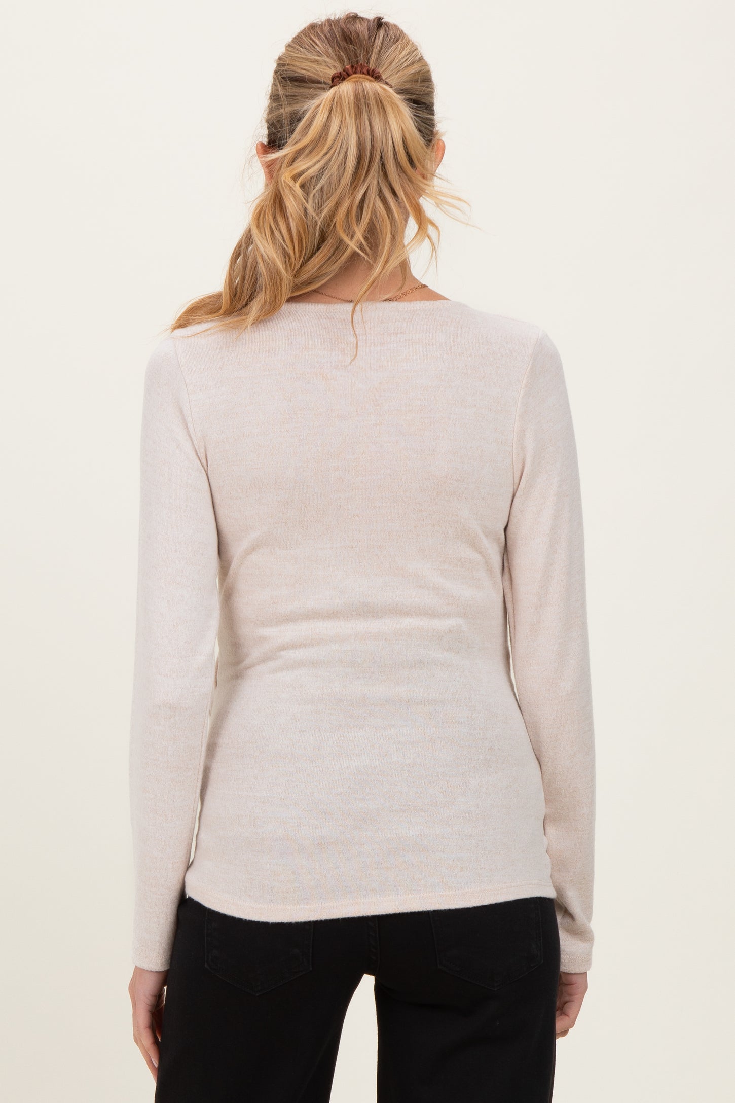 woman wearing a light beige long sleeve maternity top, view from the back