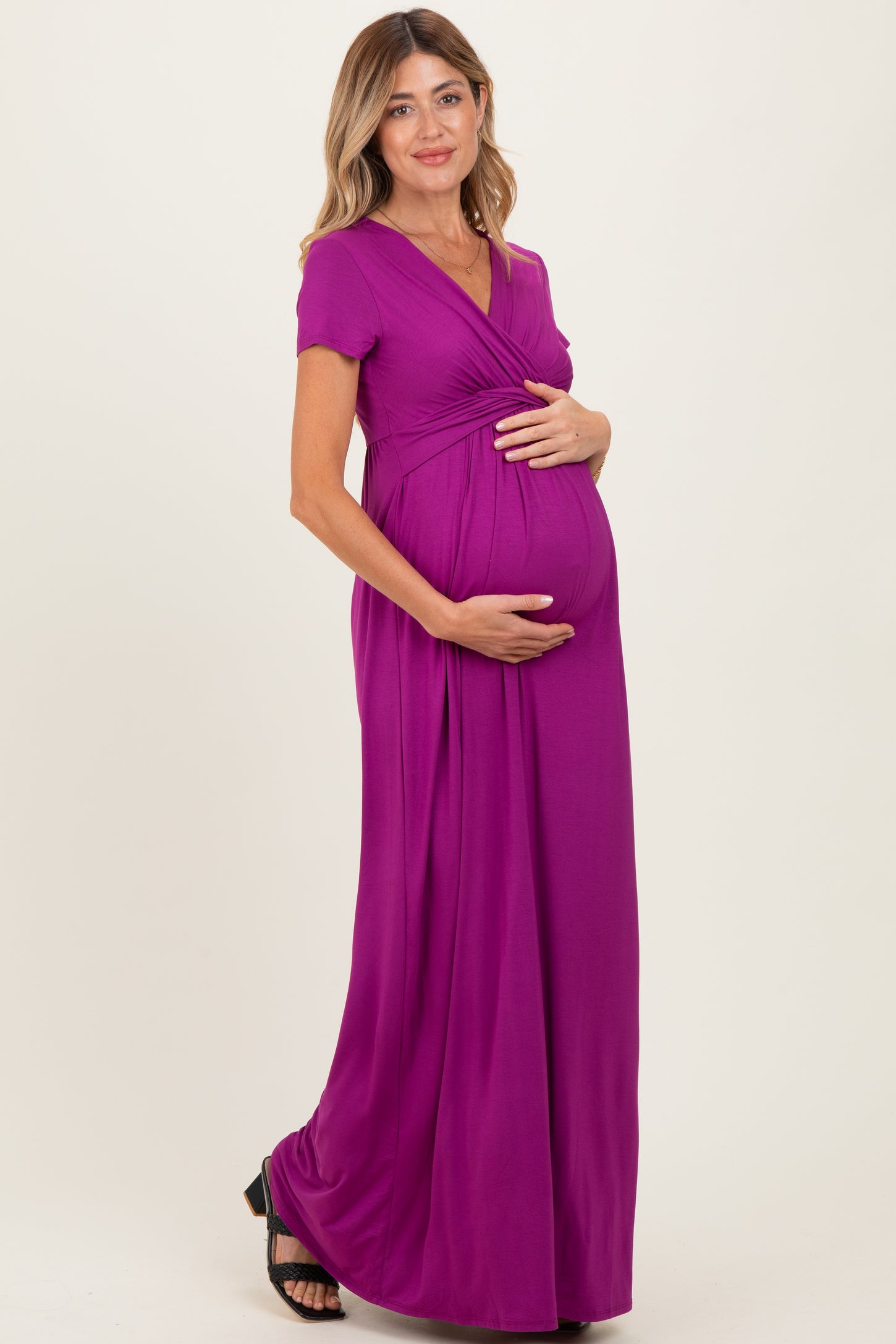 woman wearing a purple short sleeve maternity maxi dress and holding her baby bump