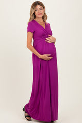 woman wearing a purple short sleeve maternity maxi dress and holding her baby bump