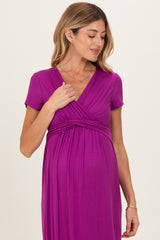 woman wearing a purple short sleeve maternity dress with a gathered waist and v-neckline, showcasing her baby bump
