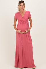 woman wearing a pink short sleeve maternity maxi dress and holding her baby bump