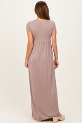 woman wearing a taupe short sleeve maxi dress with a fitted bodice and flowy skirt from the back