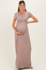 woman wearing a taupe short sleeve maternity maxi dress and holding her baby bump