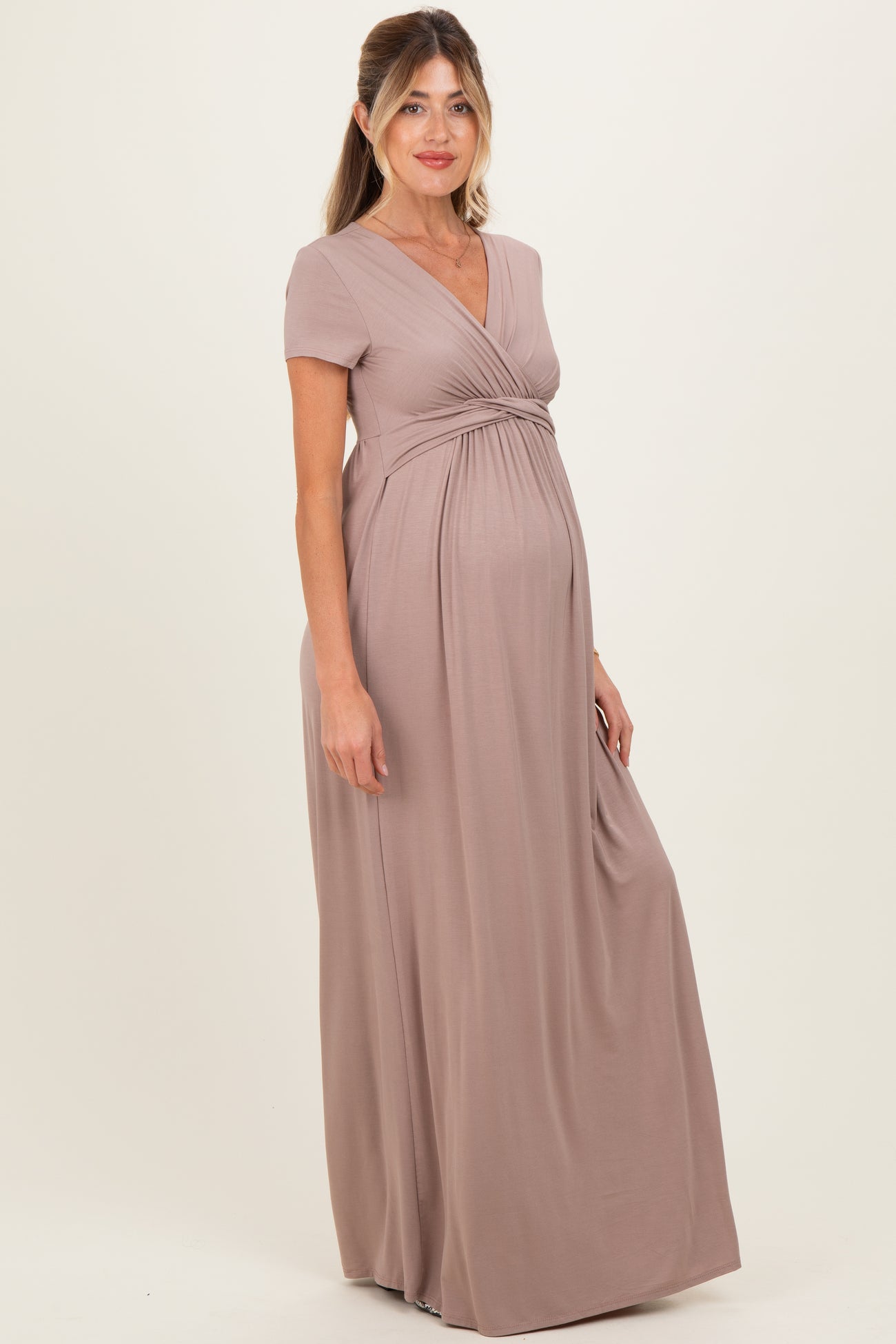 woman wearing a taupe short sleeve maternity maxi dress showcasing her baby bump