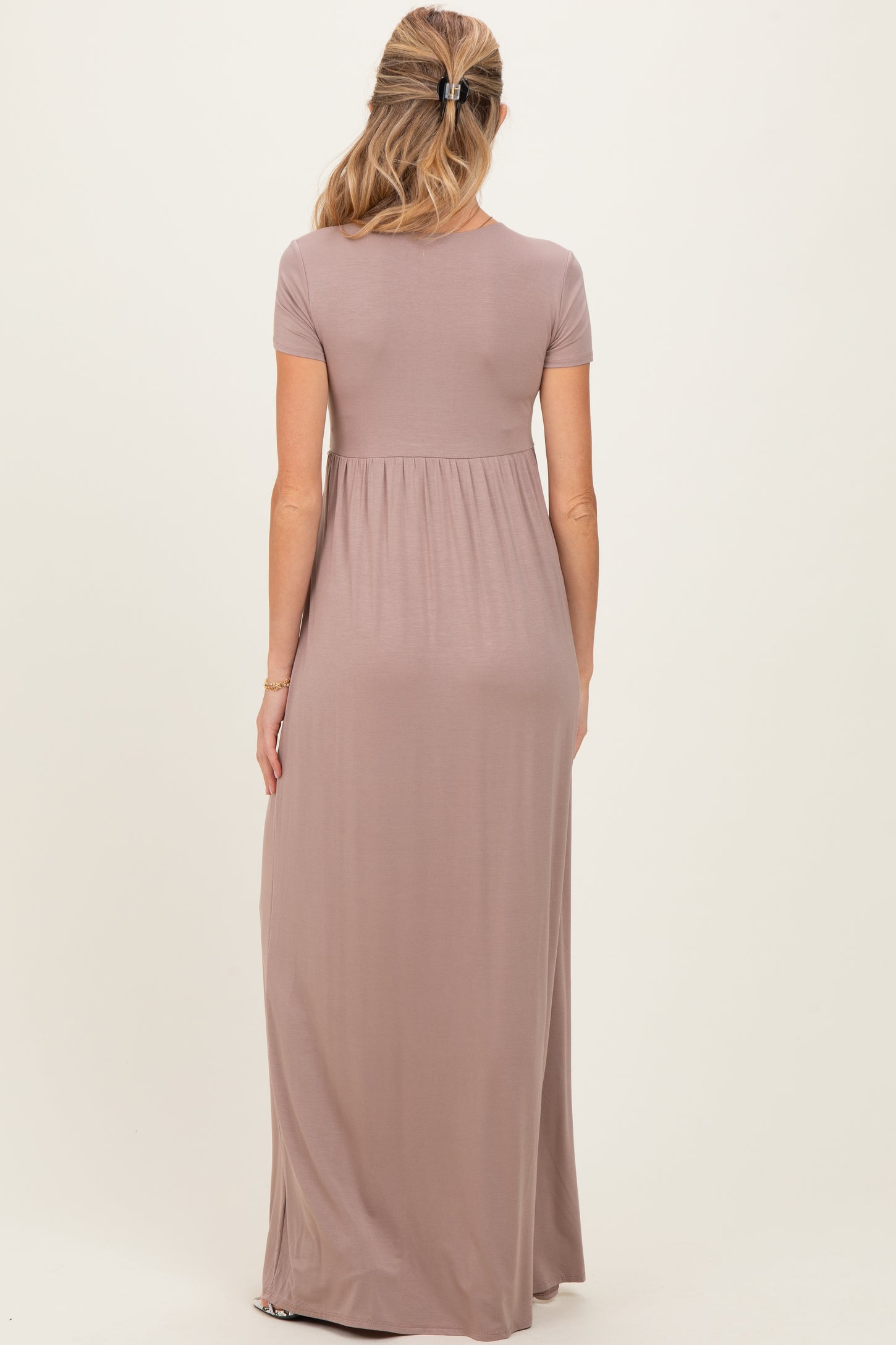 woman wearing a mauve short sleeve maternity maxi dress, showing the back view and a flowing silhouette