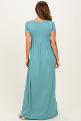 woman wearing a teal short sleeve maxi dress with a fitted bodice and flowing skirt seen from the back