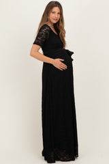 woman wearing a black lace maternity gown with short sleeves and a bow detail, showcasing her baby bump