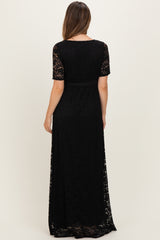 woman wearing a black lace maternity maxi dress with short sleeves and a waist tie, showing the back view