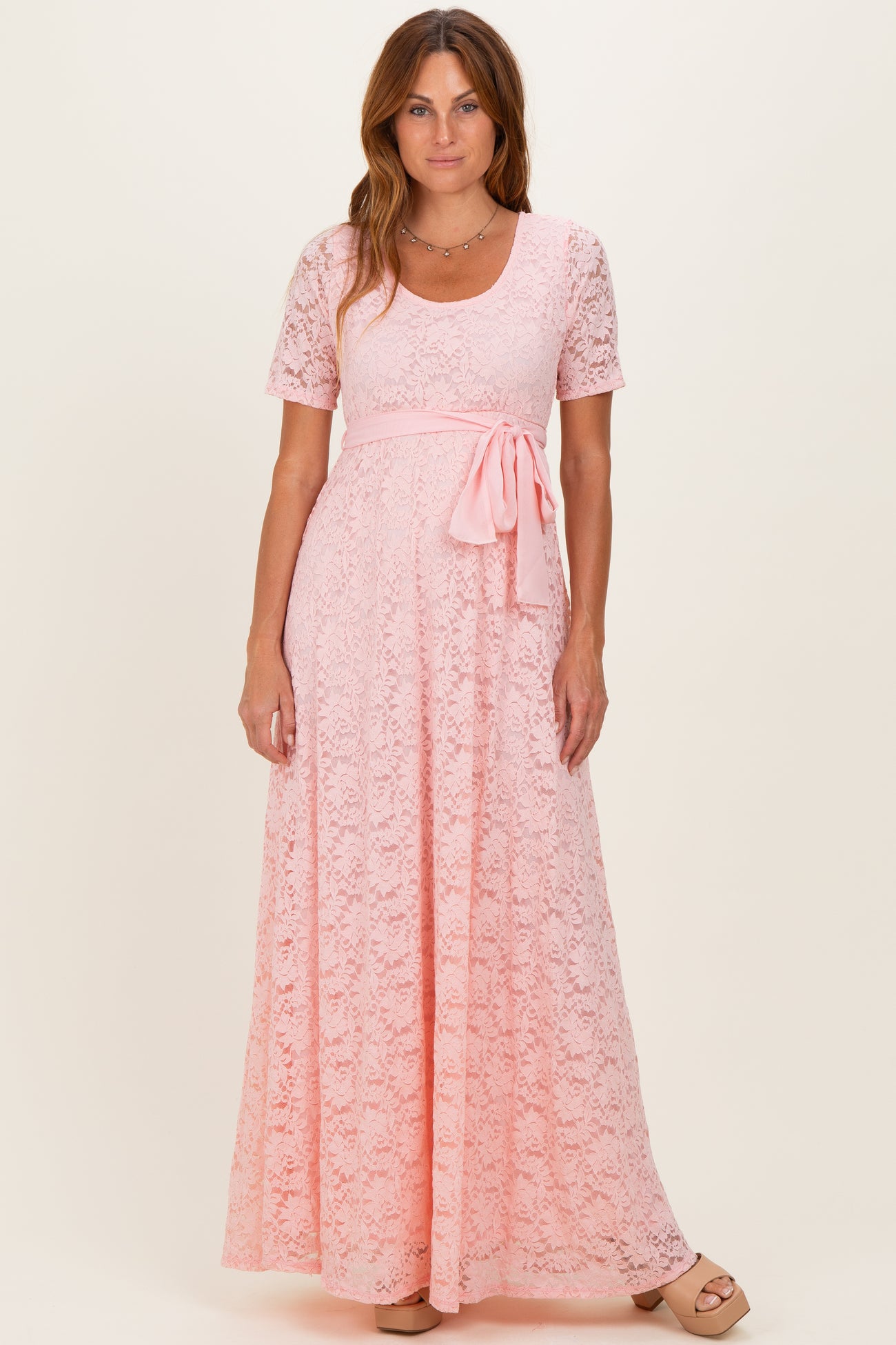 woman wearing a pink lace maxi dress with short sleeves and a waist tie detail
