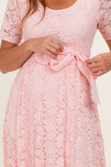 woman wearing a pink lace dress with short sleeves and a satin bow at the waist