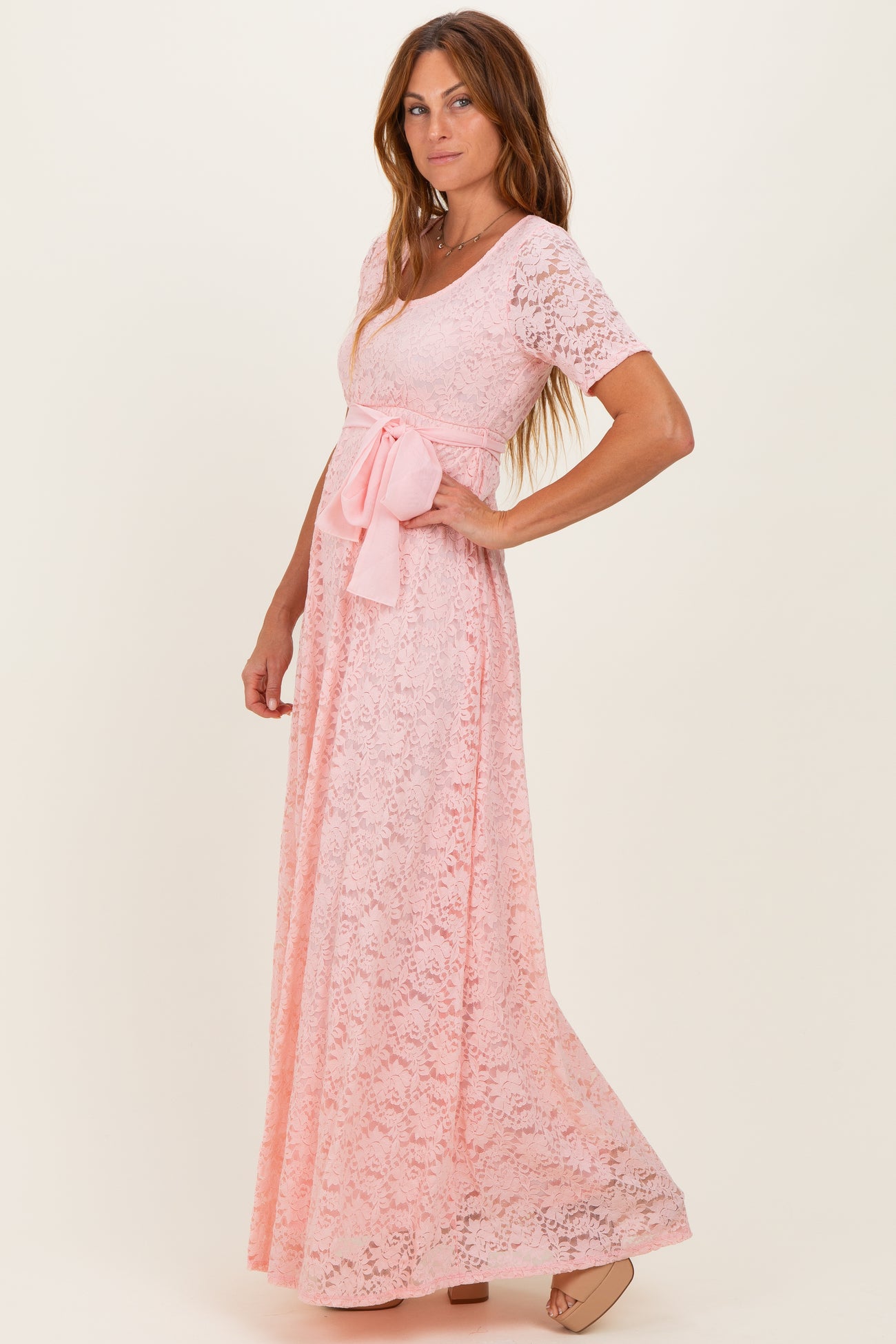 woman wearing a pink lace maxi dress with a tie waist and short sleeves